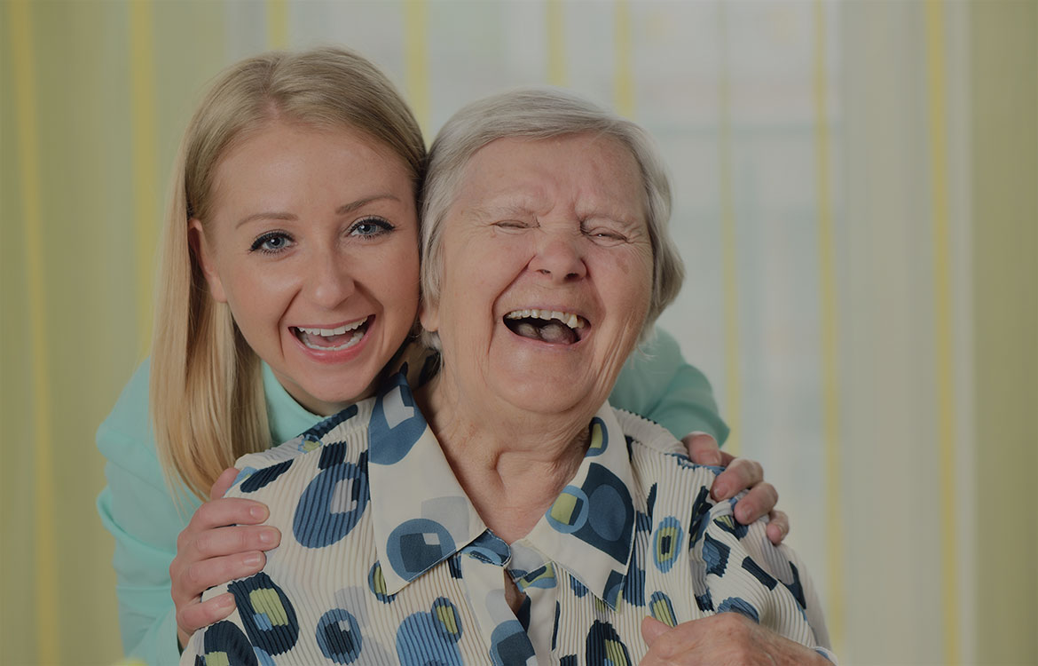 senior and caregiver laughing together
